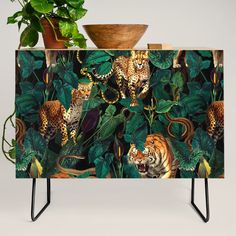 an animal themed sideboard with jungle animals and plants on it, along with a potted plant