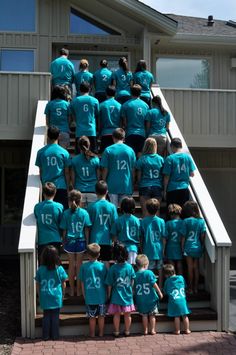 a large group of people in blue shirts standing on steps with numbers painted on them