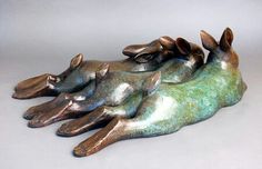 three metal animals laying on top of each other in the shape of four feet, with their tails curled up