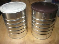 two metal containers sitting on top of a wooden table