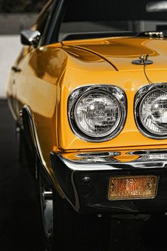 the front end of a yellow car with its lights on and headlamps down