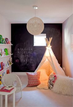 a child's room with a teepee tent and bookshelves on the wall