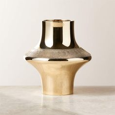 a gold and black vase sitting on top of a table