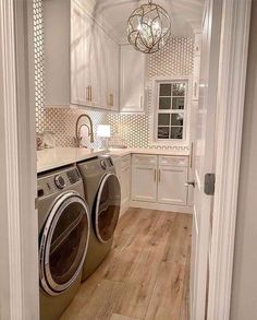 a washer and dryer in a white kitchen with wood flooring on the side