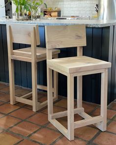 two wooden chairs sitting next to each other on a tile floor in front of an island