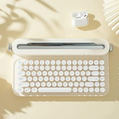 an old typewriter sitting on top of a table next to a plant and ear buds