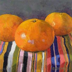 three oranges sitting on top of a striped cloth