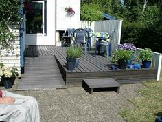 a man sitting on top of a wooden deck next to a garden filled with potted plants