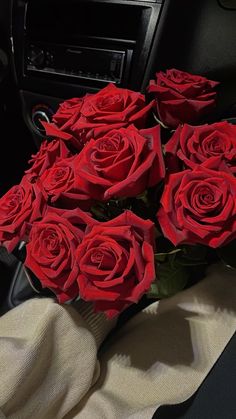 a bunch of red roses sitting in the center console of a car, ready to be picked up