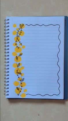 an open notebook with yellow flowers on the side and blue lined paper attached to it