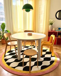 a white table with yellow chairs and a black and white rug in front of it