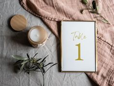 the table number is displayed next to an empty candle and some flowers on a bed