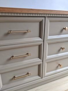 a gray dresser with brass handles and knobs