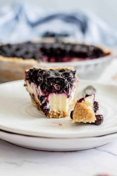 a slice of blueberry cheesecake on a white plate with a bite taken out