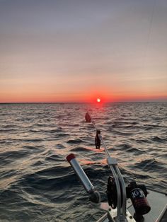 the sun is setting over the ocean as people are on a boat in the water