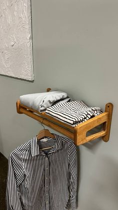 there is a bed and shirt hanging on the clothes rack in this room with grey walls