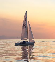 a sailboat is sailing in the ocean at sunset