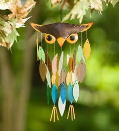 an owl mobile hanging from a tree with leaves on it's back and eyes open