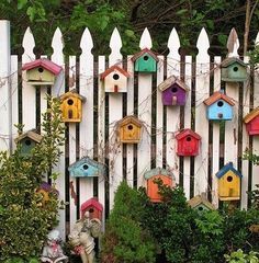 a white picket fence with colorful bird houses on it