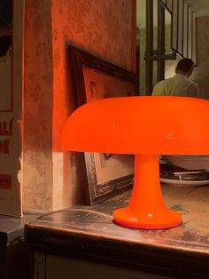 an orange lamp sitting on top of a counter next to a framed photo and other items