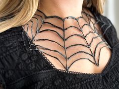 a woman wearing a spider web choker necklace on her left shoulder and black dress