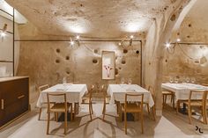 an empty restaurant with tables and chairs in the center, surrounded by exposed stone walls