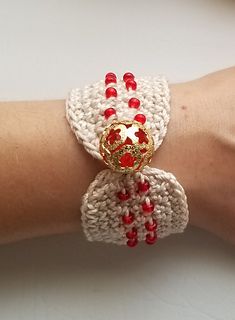 a woman's arm wearing a bracelet with red beads and a gold heart on it