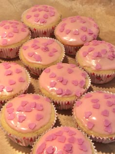 there are many cupcakes with pink frosting on the top and hearts on the bottom