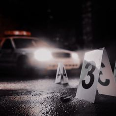 three numbered signs sitting on the side of a road in front of a police car