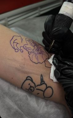 a tattoo artist with scissors on his arm and the outline of a cartoon character drawn on it