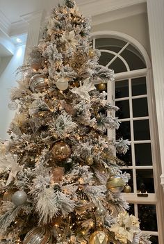 a white christmas tree with gold and silver ornaments