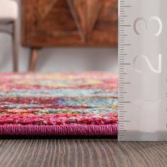 a ruler is on the floor next to a colorful area rug that's measuring