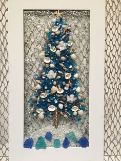 a christmas tree made out of sea glass and seashells in a white frame