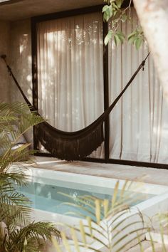 a hammock hanging from the side of a house next to a swimming pool