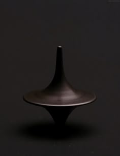 a black vase sitting in the middle of a dark room with no one around it