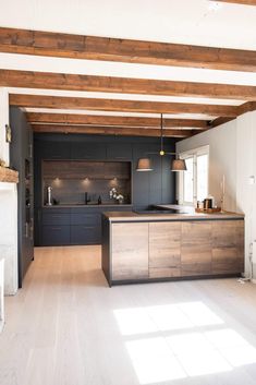 an open kitchen and dining area with wood flooring, white walls and beams on the ceiling