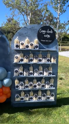 an outdoor display with balloons and confections for sale on the grass in front of trees