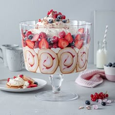 a cake with strawberries and cream on top is sitting on a table next to other desserts