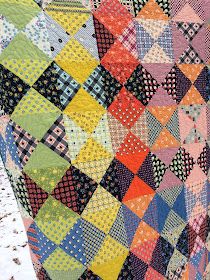 a colorful quilt is hanging on the side of a pole in front of some snow