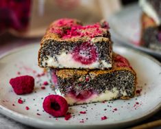 two pieces of cake on a plate with raspberries