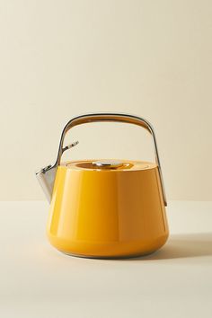 a yellow tea kettle sitting on top of a white table