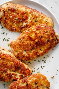 three pieces of chicken on a plate with parsley sprinkled on the top