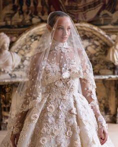 a woman in a wedding dress with a veil over her head and flowers on it