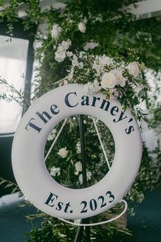 a white life preserver sitting on top of a table next to flowers and greenery