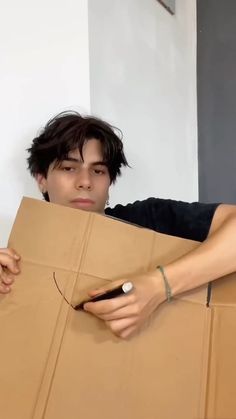 a young man is holding a cardboard box