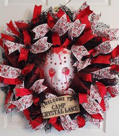 a red and black wreath with a white mask on it that says welcome to camp crystal lake