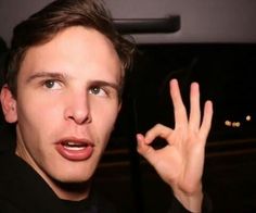 a young man making the peace sign with his hand while sitting in a car at night