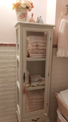 a white cabinet in a bathroom with towels on it