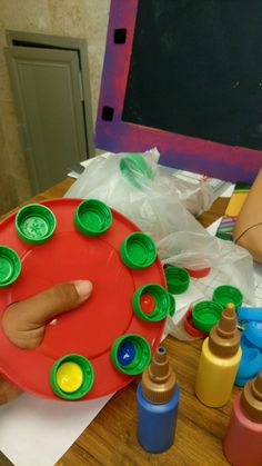 a child's hand on a red plate surrounded by crayons