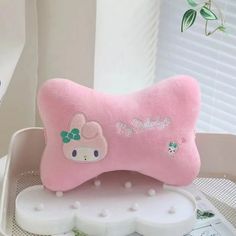 a pink hello kitty bone shaped pillow sitting on top of a white tray next to a window